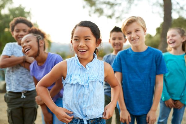 Das Foto zeigt eine lachende, diverse Kindergruppe.