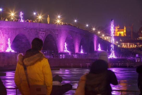 Menschen an Steinerner Brücke bewundern Lichtkunstwerk