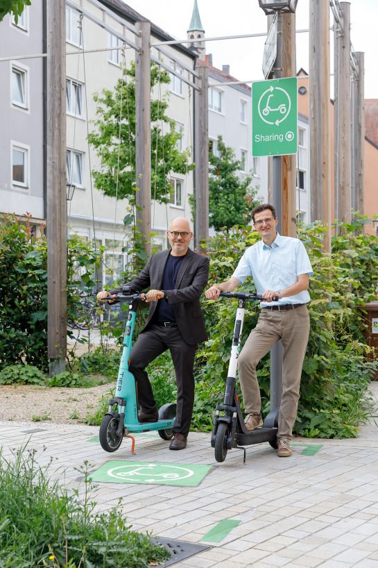 Fotografie: Planungs- und Baureferent Florian Plajer und Nahmobilitätskoordinator Thomas Großmüller auf einem Abstellplatz für E-Scooter