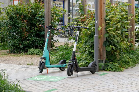 Fotografie: Zwei E-Scooter stehen auf einem Abstellplatz.