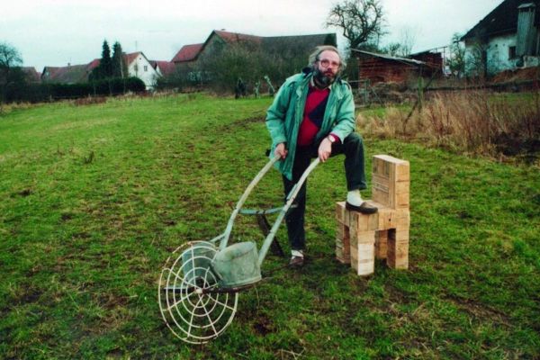 Fotografie - Max Bresele in Natur mit Holzstuhl und „Karren der Depression“