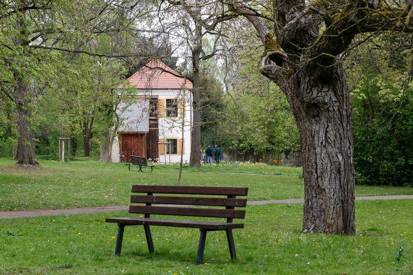 Fotografie - Sitzbank im Vordergrund, dahinter kleines Haus, das Salettl