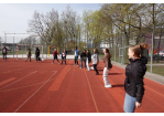 Auf dem Foto sind mehrere Mädchen auf einem Sportplatz zu sehen, welche Aufwärmspiele spielen.