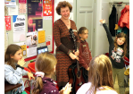 Henriette Wich steht mit einer Gitarre umringt von Kindern im Café Klara