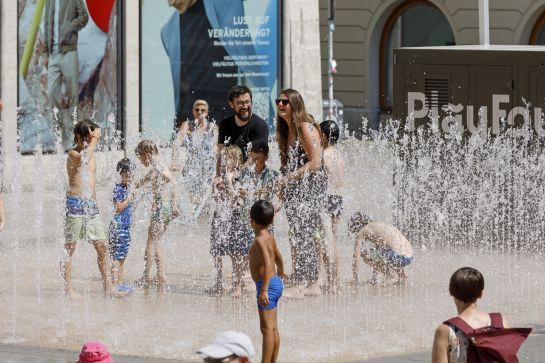 Eltern und Kinder genießen das Wasserspiel am Neupfarrplatz.