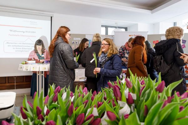 Fotografie - Besuchende bei der Messe im Raum für Engagement mit violetten Tulpen 